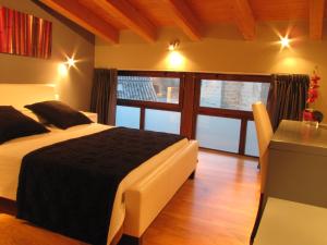 a bedroom with a bed and a desk and a window at Hotel Portal Del Matarraña in Valjunquera