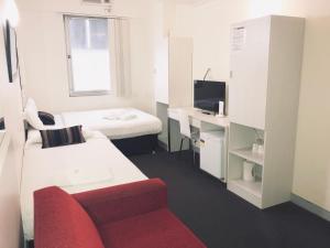 een kleine kamer met 2 bedden en een rode bank bij Turbot House Hotel in Brisbane