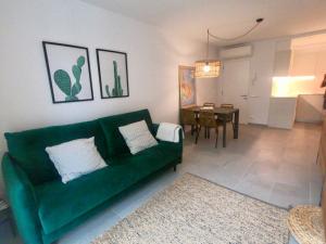 a living room with a green couch and a table at Apartamento nuevo en el centro con garaje in Cadaqués