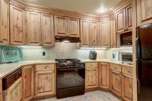 kuchnia z drewnianymi szafkami i kuchenką z piekarnikiem w obiekcie Cozy & Central Arrowhead Village Townhome Condo w mieście Edwards +22 zdjęcia