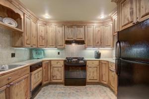 a kitchen with wooden cabinets and a black refrigerator at Cozy & Central Arrowhead Village Townhome Condo in Edwards