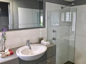 a white bathroom with a sink and a shower at Sacred Mountain Retreat in Nambucca Heads