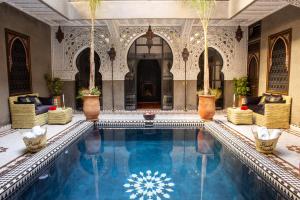 a swimming pool in a palace with chairs and plants at Riad Touda in Marrakech