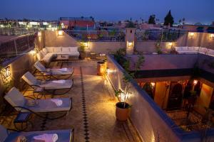 a rooftop patio with tables and chairs at night at Riad Touda in Marrakech