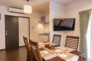 a dining room with a table and a television on the wall at 還元ホテル 名護大宮 in Nago