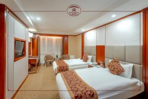 um quarto de hotel com duas camas e uma televisão em Royal House Hotel em Ulan Bator