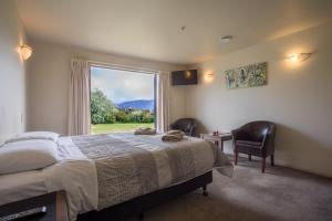 a bedroom with a bed and a large window at Loch Vista Bed & Breakfast in Te Anau