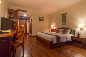 a bedroom with a bed and a desk and a television at Khemara Angkor Hotel & Spa in Siem Reap