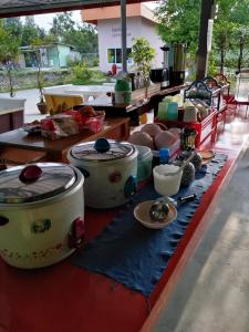 un tavolo con molte pentole e piatti sopra di บ้านฟ้ารักตะวัน a Petchaburi