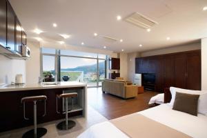 a bedroom with a bed and a kitchen with a view at Tropical Dream Spa Resort in Geoje 