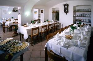 un restaurante con mesas blancas y sillas con comida. en Equin'Ozio, en Castellamonte