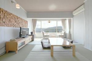 ein Wohnzimmer mit einem TV und einem Tisch in der Unterkunft Hotel Ra Kuun in Hakone