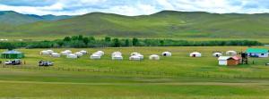 een groep witte tenten in een veld met bergen bij orkhon camp in Burgaasatayn Hiid
