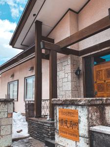 a house with a sign in front of it at Hostel Jumpu Manpan in Otaru