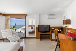a living room with a couch and a tv in a room at Beluga Boutique Hotel in Lamai