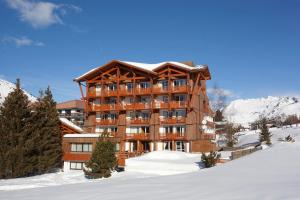 un gran edificio de madera en la nieve con nieve en Le Souleil'Or, en Les Deux Alpes