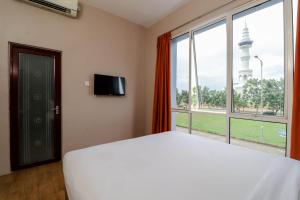 瑟古邦Blitz Hotel Batam Near Sultan Mahmud Ri'ayat Shah的卧室里有一张白色的床和一扇大窗户