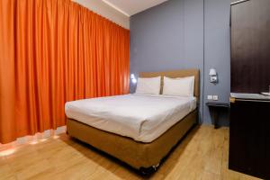 瑟古邦Blitz Hotel Batam Near Sultan Mahmud Ri'ayat Shah的一间卧室配有一张带橙色窗帘的床