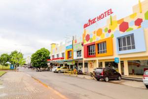 瑟古邦的住宿－Blitz Hotel Batam Tanjung Uncang，一条在大楼前停放汽车的街道