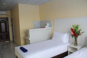 una habitación de hotel con 2 camas y un jarrón con flores en Central Bay Motel en Port Vila