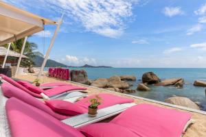a group of pink lounge chairs on the beach at Beluga Boutique Hotel in Lamai