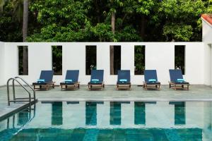 a row of blue lounge chairs next to a swimming pool at Mantra Koodam Kumbakonam - a CGH Earth Experience in Kumbakonam