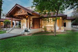 a house with a porch and a grass yard at Mantra Koodam Kumbakonam - a CGH Earth Experience in Kumbakonam