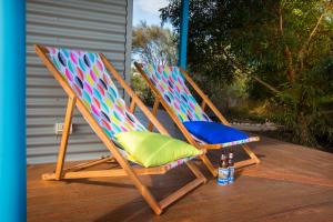 a pair of deck chairs with a bottle of beer at Coorong Cabins in Meningie