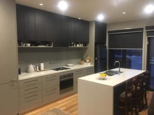 a kitchen with black cabinets and a white counter top at Central apartment with stairs in Ballarat