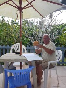 un hombre sentado en una mesa comiendo una rosquilla en Dayspring Lodge en Nukualofa