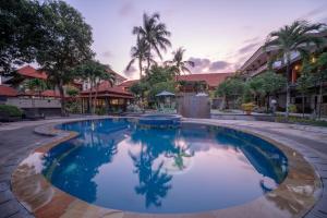 a swimming pool at a resort with palm trees at Bendesa Accommodation in Kuta