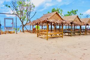 un grupo de mesas y sombrillas de paja en una playa en Lanta Palm Beach Resort , Beach Front Bungalow - Koh Lanta, en Ko Lanta
