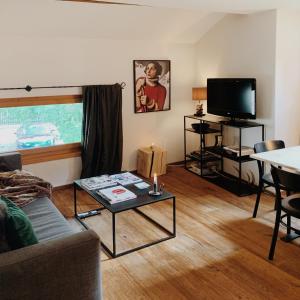 a living room with a couch and a table and a tv at Apartment Euforia in Samedan