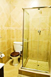 a bathroom with a toilet and a glass shower at Rip van Winkel Guest House in Lephalale +33 photos