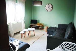 a living room with a couch and a clock on the wall at SWEET HOME, LOUTRA POZAR in Dorothéa