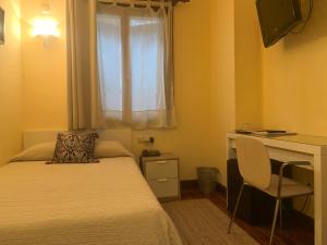 a bedroom with a bed and a desk and a window at Hotel Alameda in Zarautz