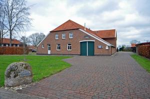 a brick building with a green door and a brick driveway at Ferienwohnung im Gulfhof, 65269 in Moormerland