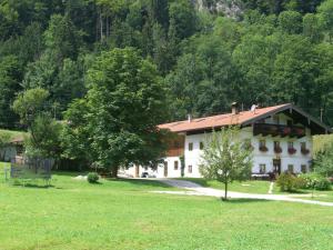 ein großes weißes Haus auf einem Feld mit Bäumen in der Unterkunft Ferienwohnungen Landinger in Aschau im Chiemgau
