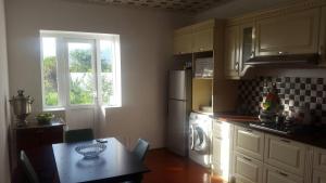 a kitchen with a table and a refrigerator and a window at Ismayilli Holiday House in İsmayıllı