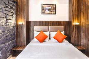 a bedroom with a bed with orange and white pillows at Hotel Sea Grand, Colaba in Mumbai