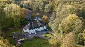 eine Luftansicht eines großen weißen Hauses im Wald in der Unterkunft Hotel Wintersmühle in Bielefeld