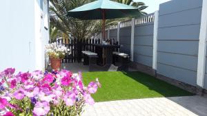 a patio with a table with an umbrella and flowers at Maggie´s Accommodation in Swakopmund