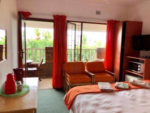 a bedroom with a bed and a balcony with red curtains at Seaside Lodge B&B in Ballito