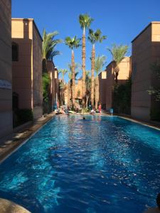 - une piscine dans un complexe avec des palmiers dans l'établissement Riad BAB ALMADINA, à Marrakech