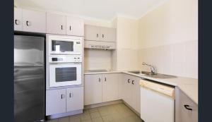 una cocina con armarios blancos y electrodomésticos de acero inoxidable en 181 The Esplanade, en Cairns