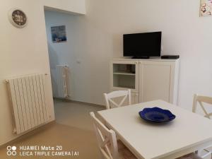comedor blanco con mesa blanca y TV en CIVICO 63, en Brindisi