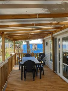 a wooden deck with a table and chairs on it at Camping les dunes de contis in Saint-Julien-en-Born