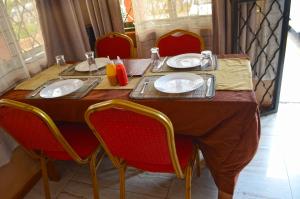 a table with red chairs and plates on it at Saltek Forest Cottages in Masindi