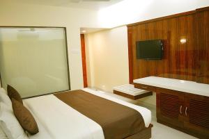 a bedroom with a large bed and a television at Hotel Milan International in Mumbai