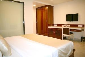 a bedroom with a bed and a desk with a television at Hotel Milan International in Mumbai